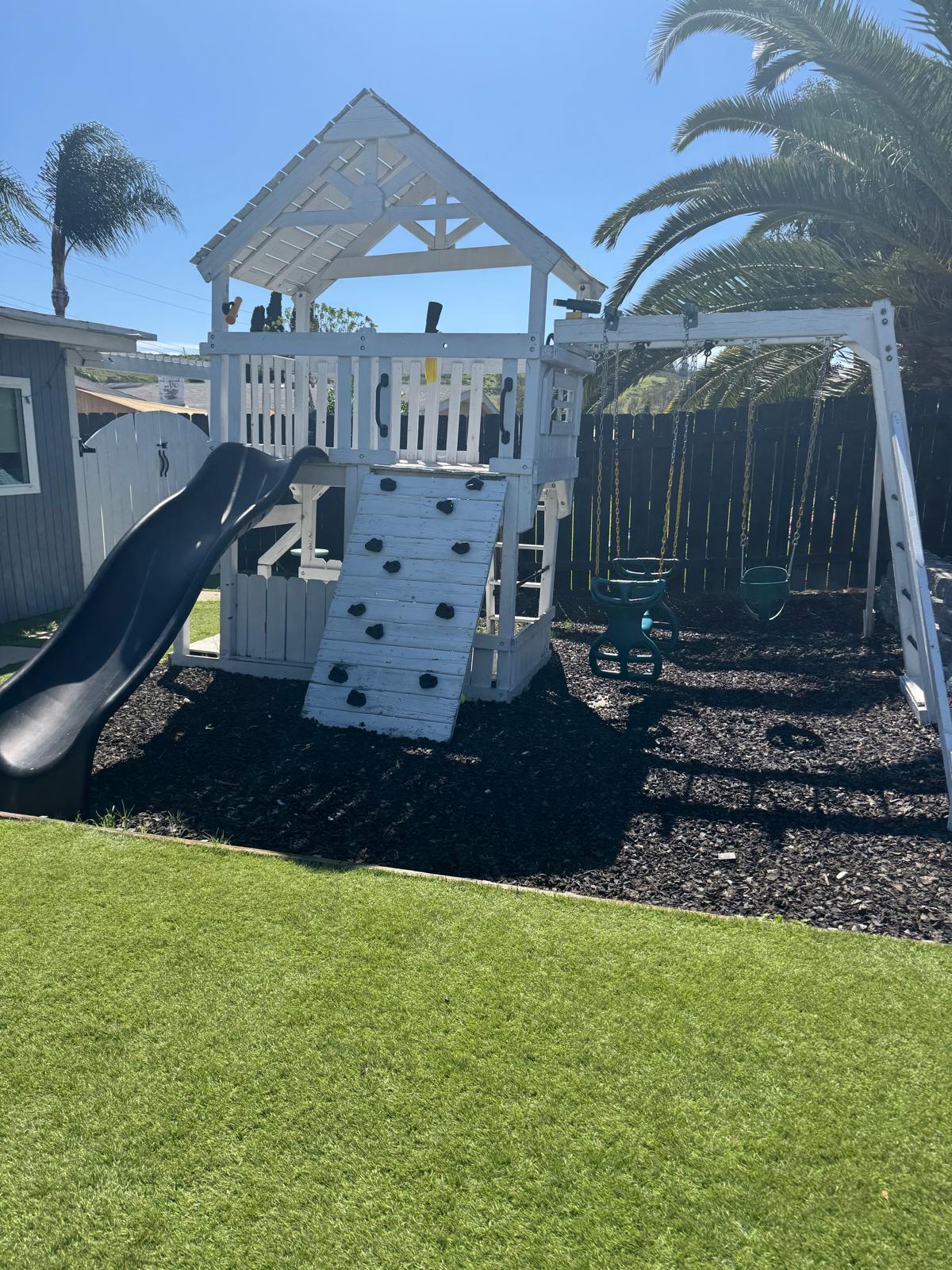 Outdoor play area with climbing structure and soft turf